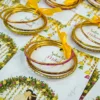 Close-up of gold glass bangles tied with yellow ribbon on favour card