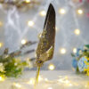 Sleek polished gold handle beneath a gold-speckled dark feather