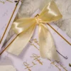 Gold ribbon bow attached to Islamic wedding favour cards