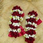 Close-up of deep red velvet roses and delicate white floral details on bridal gajray