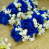 Close-up of deep blue artificial roses and delicate white floral details on bridal gajray