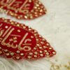 Close-up of rich gold embroidery and sparkling stonework border on dark red velvet Imam Zamin