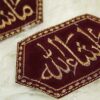 Close-up of intricate gold wavy thread work and sparkling details on dark maroon velvet Imam Zamin
