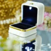 White velvet ring box sitting on a custom pink rose mirror ring tray