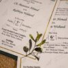 Deep green envelope with gold leaf pin holding the card set