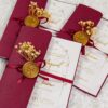 Multiple maroon wedding invitations displayed with dried baby's breath