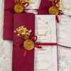 Detail of maroon satin ribbon and gold wax seal on wedding card