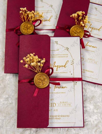 Detail of maroon satin ribbon and gold wax seal on wedding card