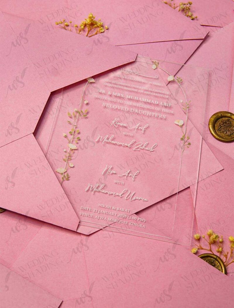 Clear acrylic wedding invitation card with floral arch design on pink envelope