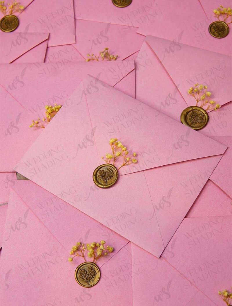 Gold wax seal on soft pink envelope holding the acrylic card