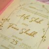 Close-up of cream card showing gold foil event details and floral design