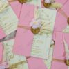 Multiple pink wedding invitation sets with dried flower decorations