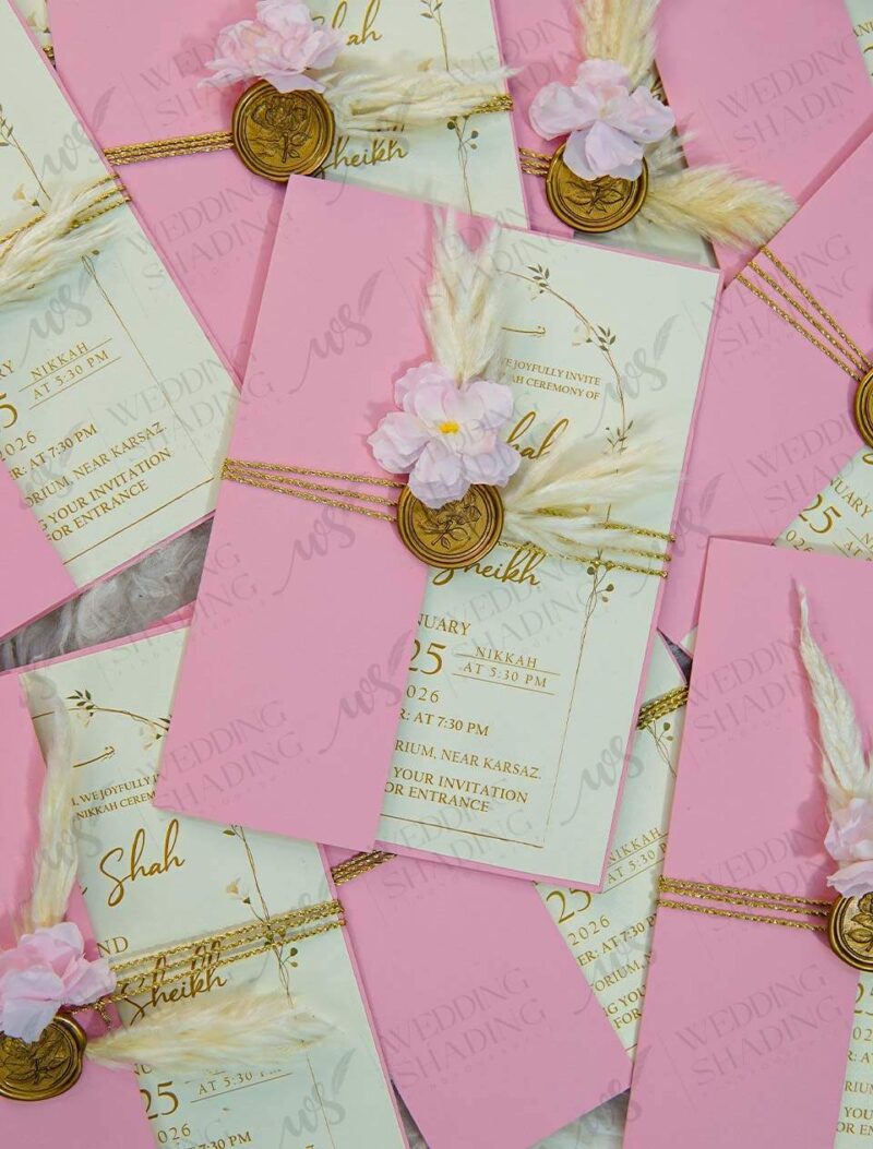 Multiple pink wedding invitation sets with dried flower decorations