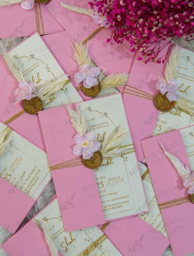 Detail view of gold wax seal and feather on soft pink wedding card