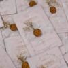 White wedding card with organza ribbon bow, wax seal, and dried flowers