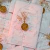 Close-up of gold floral wax seal on white translucent vellum wrap